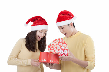 Portrait of young couple wearing Santa hats holding gifts