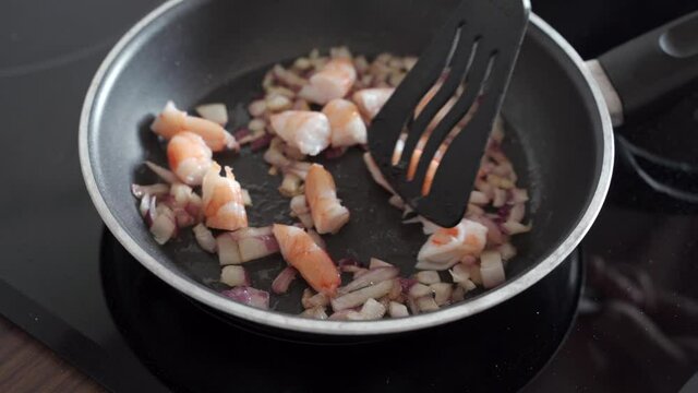 Shrimps added to choped red onion on a pan, cooking video