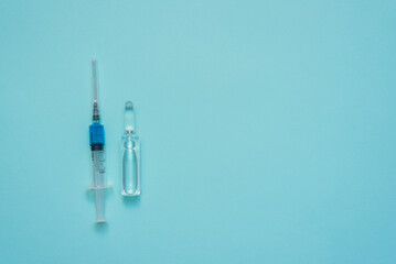 Syringe and ampoule on the blue background with copy space.