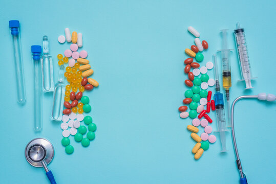 Various medical tablets and pills, syringe, stethoscope,  laboratory flask and ampoules on the blue background.