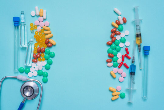 Various medical tablets and pills, syringe, stethoscope,  laboratory flask and ampoules on the blue background.