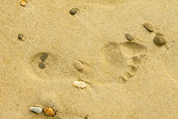 Single foorprint in yellow brown sand on the beach as a symbol for recreation or vacations