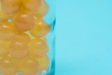 Fish fat capsules in the transparent glass bottle on the blue background.