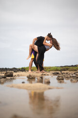 Happy couple in love dances at the beach during their engagement vacation