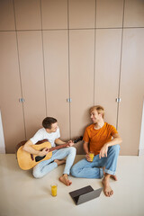 Handsome young man playing guitar for his boyfriend at home