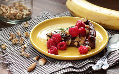 Chocolate vegan brownie cake with banana decorated with raspberry, walnut and rosemary, closeup, copy space, vegan eggfree desserts concept