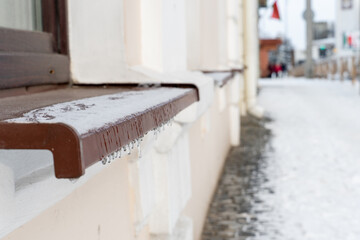 The facade of the building and window sills are covered with ice and snow. Severe frosts and a lot of snow in the city after a snowstorm and blizzard. danger of icicles falling from roofs.