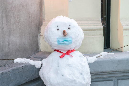 A portrait of a snowman in a medical mask. Winter concept of quarantine restrictions. The snowman is protected from the virus.
