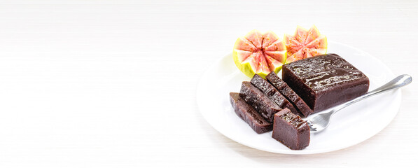 Guava jam in bar known in Brazil as Goiabada, isolated on white background, with plate and cut fruits around