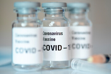 Three coronavirus vaccine vials and a syringe.