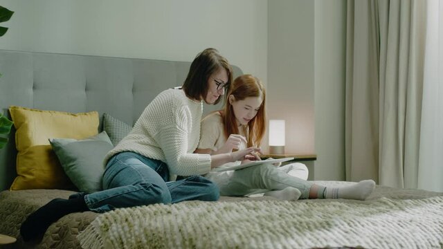 Mother and Daughter Play Game On Tablet Together