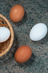 several fresh chicken eggs in a straw basket on a wooden background. Healthy eating concept.
