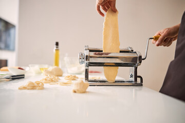 Careful cook using pasta machine in the kitchen