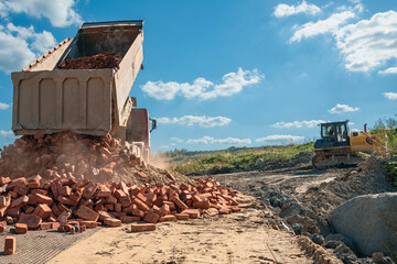 Fototapeta premium truck unloads old brick on a road under construction to a new construction site
