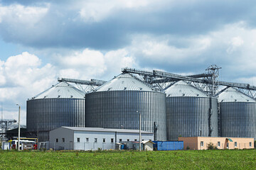Fototapeta na wymiar Granary Modern agro-processing plant for the storage and processing of grain crops Silver silos on agro manufacturing plant