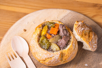 Delicious tasty hot warm homemade take away delivery beef stew red wine gravy soup sauce meal food meal with vegetable carrot potato pepper serve with bread bowl disposable wood cutlery spoon fork