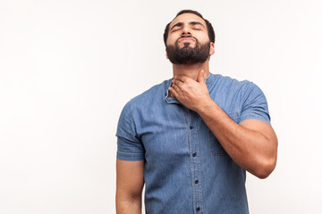 Unhappy sick man touching neck feeling pain while swallowing, result of chocking, throat inflammation, sore throat. Indoor studio shot isolated on white background