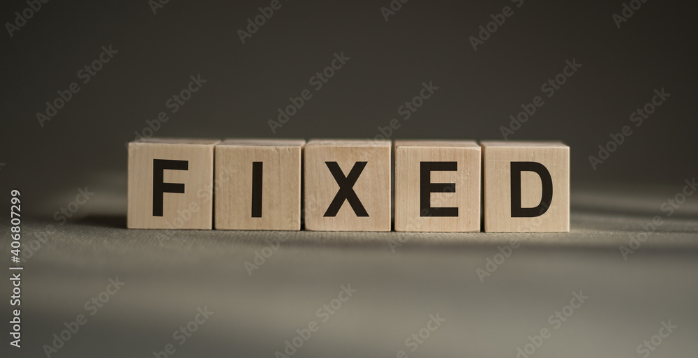 Fototapete a wooden blocks with the word fixed written on it on a gray background.