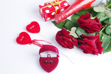 Three red roses and boxes with jewelry on a white background.