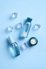 Set of hydration cosmetics and ice cubes on blue background. Flat lay, top view.