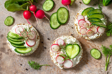 Sandwiches crispbread with ricotta, radish and fresh cucumber on a light or slate countertop. Top view flat lay background.
