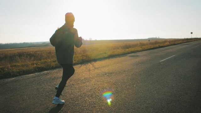 Silhouette fitness sport women running on road at sunset. Athlete runner feet running on road.