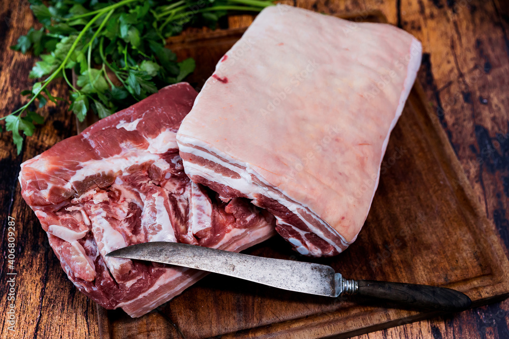 Wall mural fresh pork belly on a used cutting board resting on an old wooden table