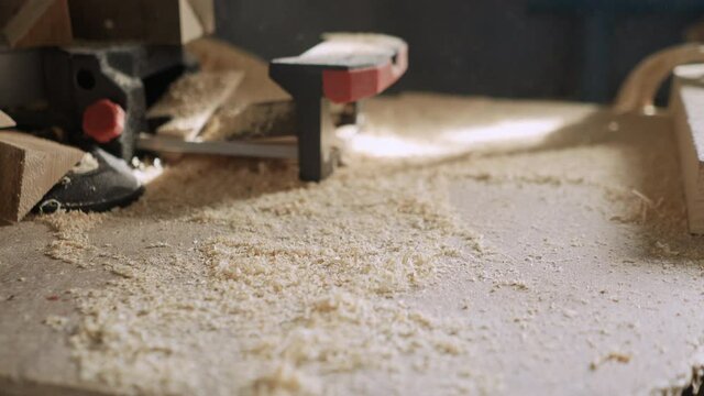 Wood blanks and wood shavings on a workbench in a carpentry workshop in the rays of light