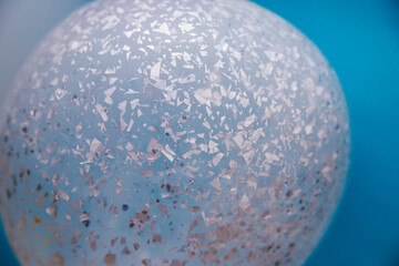 Abstract background texture, bright holographic shaped metal foil ornament inside the balloon.