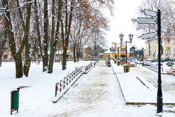 A beautiful street or alley in the park covered with snow after a snowfall. A city after a snowstorm. Beautiful lanterns and direction signs along the park staircase. An empty street without people