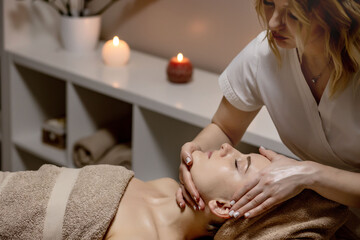 Obraz na płótnie Canvas Relaxing massage. Woman receiving head massage at spa salon, side view