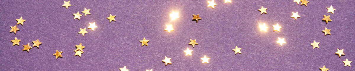 Gold stars on purple background. Yellow glitter backdrop. Golden texture. New year luxury snow. Copyspace. Shimmer confetti wallpaper. Dreamy shiny design detail