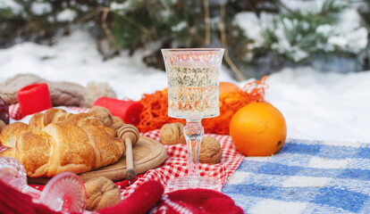 Romantic picnic setting in winter park, color blanket. Fresh food, cheese, oranges, croissants, wine and walnuts. Outdoor relaxing, fresh air eating.