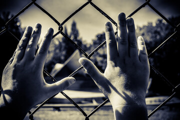 The child's hands are stretched out to the metal mesh.
