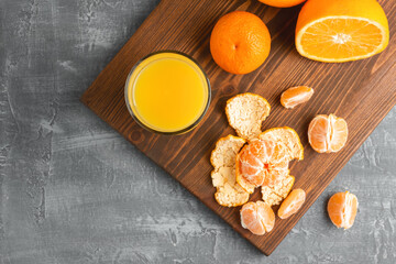 Glass of fresh orange juice, whole and sliced fruits on wooden board, top view with copy-space