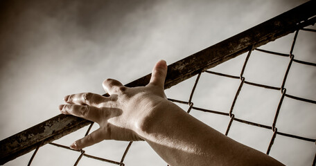 The man's hands are stretched out to the metal mesh.