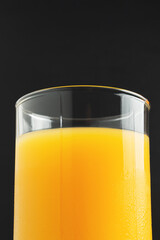 Glass of fresh orange juice on dark background