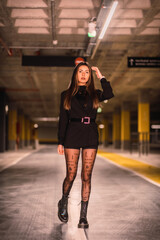 Young caucasian model with black jacket posing in an empty underground car park. Night urban session in the city