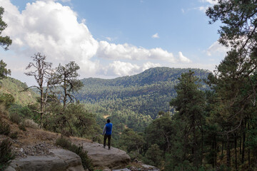Naklejka na ściany i meble Male hiker standing on rocks on the Iztaccihuatl mountain covered in greenery in Mexi