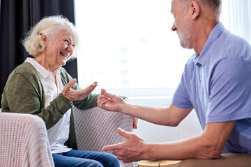 elderly husband made a surprise for his wife, please her, a gray haired man is presenting gift to elderly pleasantly surprised woman, give ring