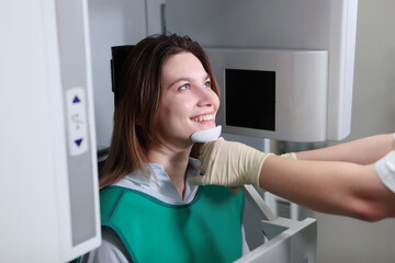 The dentist prepares the patient for a panoramic x-ray of the teeth. X-ray equipment in the clinic. Health care concept. Girl in a protective vest.