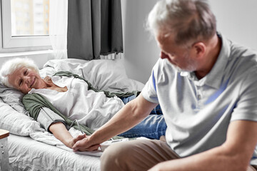 senior man visiting his sick wife at hospital ward, support and help. health, medicine concept