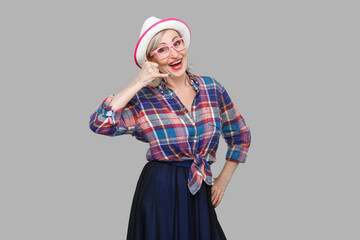 Portrait of funny modern stylish mature woman in casual style with hat and eyeglasses standing with...