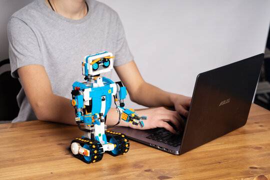 Minsk, Belarus. January 2021. A teenage boy programs a Lego Boost robot on a laptop. A teacher helps him. STEM education. DIY. AI.