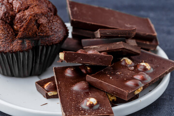 Chocolate cupcake with icing and chocolate bar in Dark lighting,Homemade delicious chocolate muffin on wooden background close-up