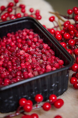 red frozen berries lie in a black dish on a wooden table side view
