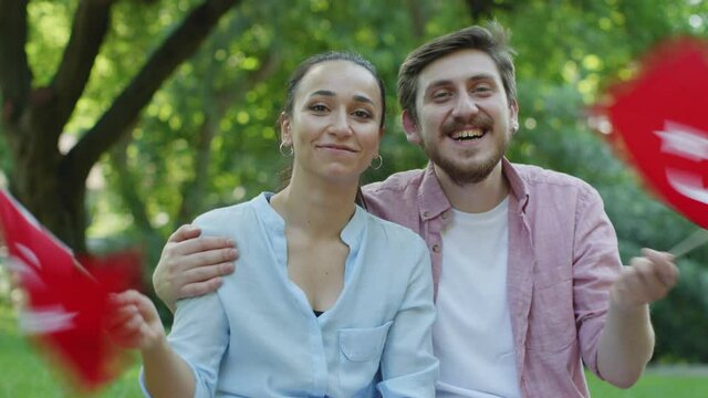 Two young people are waving the Turkish flag while looking at the camera.	Young people waving a Turkish flag at the camera.