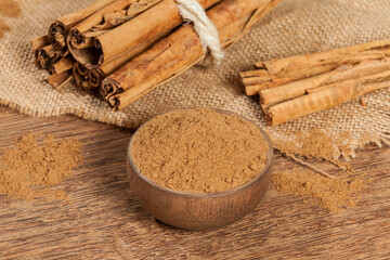 Cinnamon powder and cinnamon stick; photo on wooden background.