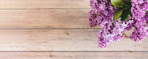 Lilac flowers on rustic wooden background. Top view, flat lay, copy space. Spring concept. Banner.