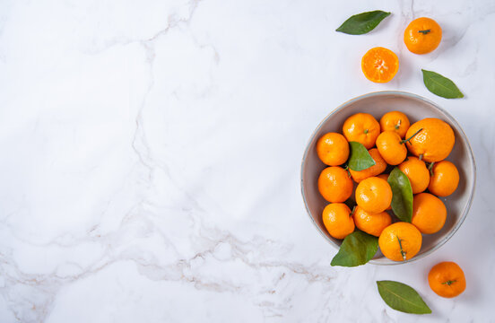 Flat lay sweet tangerines in a ceramic bowl on a white marble background © Ольга Кучкина